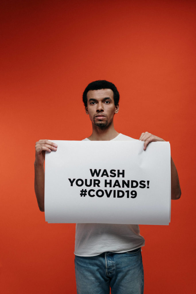 man holding a sign for guidance against coronavirus 3952194 683x1024 1