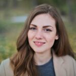 Close-up portrait of a smiling woman with freckles and long hair in a Budapest park during fall.